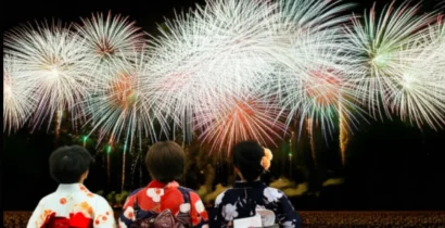 夏の夜空を彩るナイアガラの滝のような壮大な花火を眺める、色とりどりの浴衣を着た3人の女性の後ろ姿。