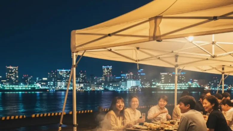 博多ベイサイドの夜景と楽しむ冬季限定の牡蠣小屋 博多ベイサイドの夜に灯る牡蠣小屋のテントと焼き牡蠣の雰囲気が伝わる写真