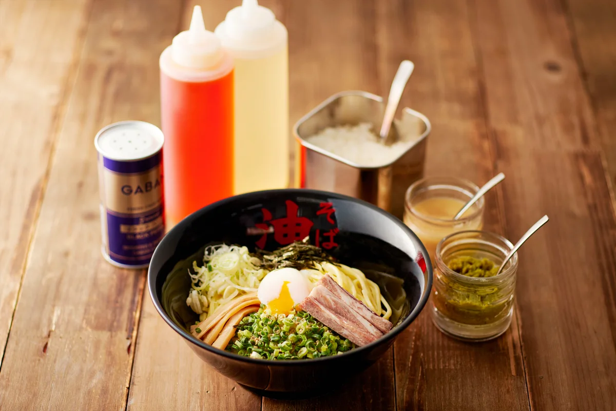 油そばの無料トッピング 東京油組総本店の油そばと無料トッピングの調味料が並んだ写真
