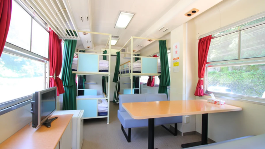 TR列車の宿 4名タイプ客室 TR列車の宿の4名タイプ客室。車内に2段ベッドとソファ席、テーブルが並ぶ